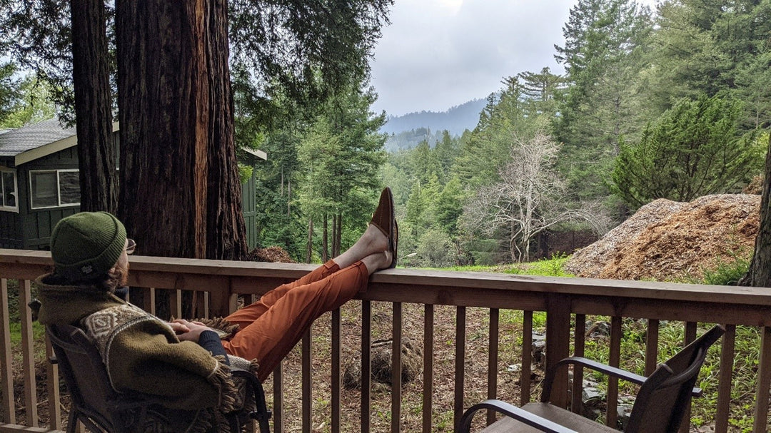 man sitting on a deck in the woods looking at trees